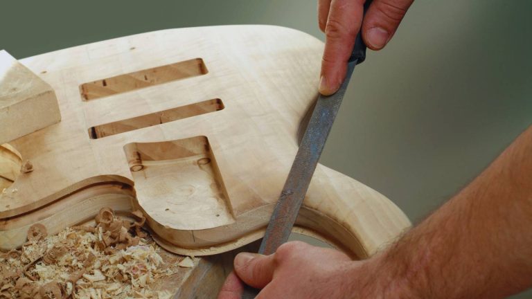 Imagen del Luthier Rayco Martín trabajando sobre un trozo de madera que se está convirtiendo en el cuerpo de una guitarra
